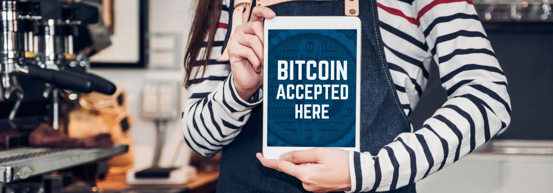 Woman holding tablet we accept bitcoin on screen